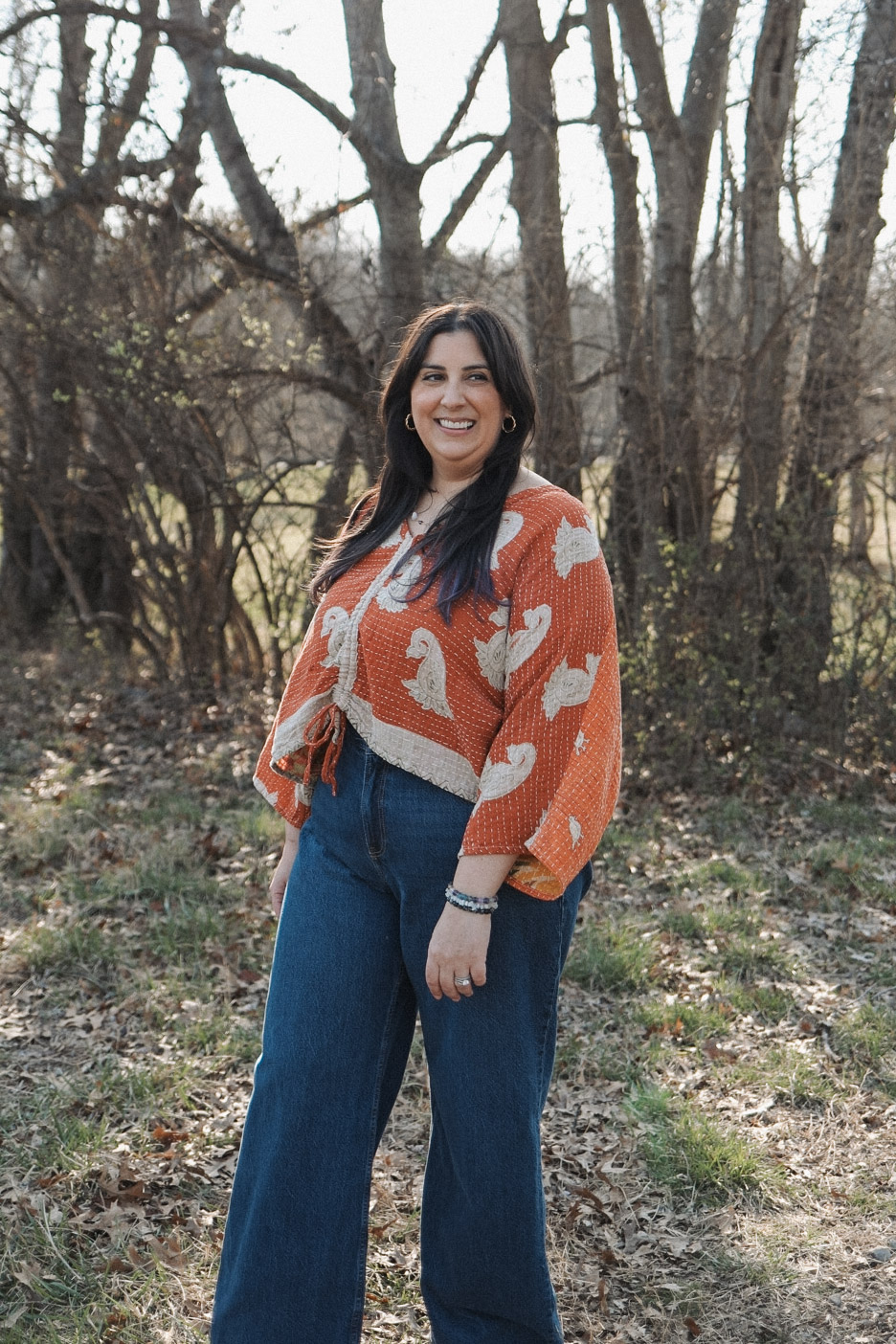 Christina standing outdoors among trees, smiling